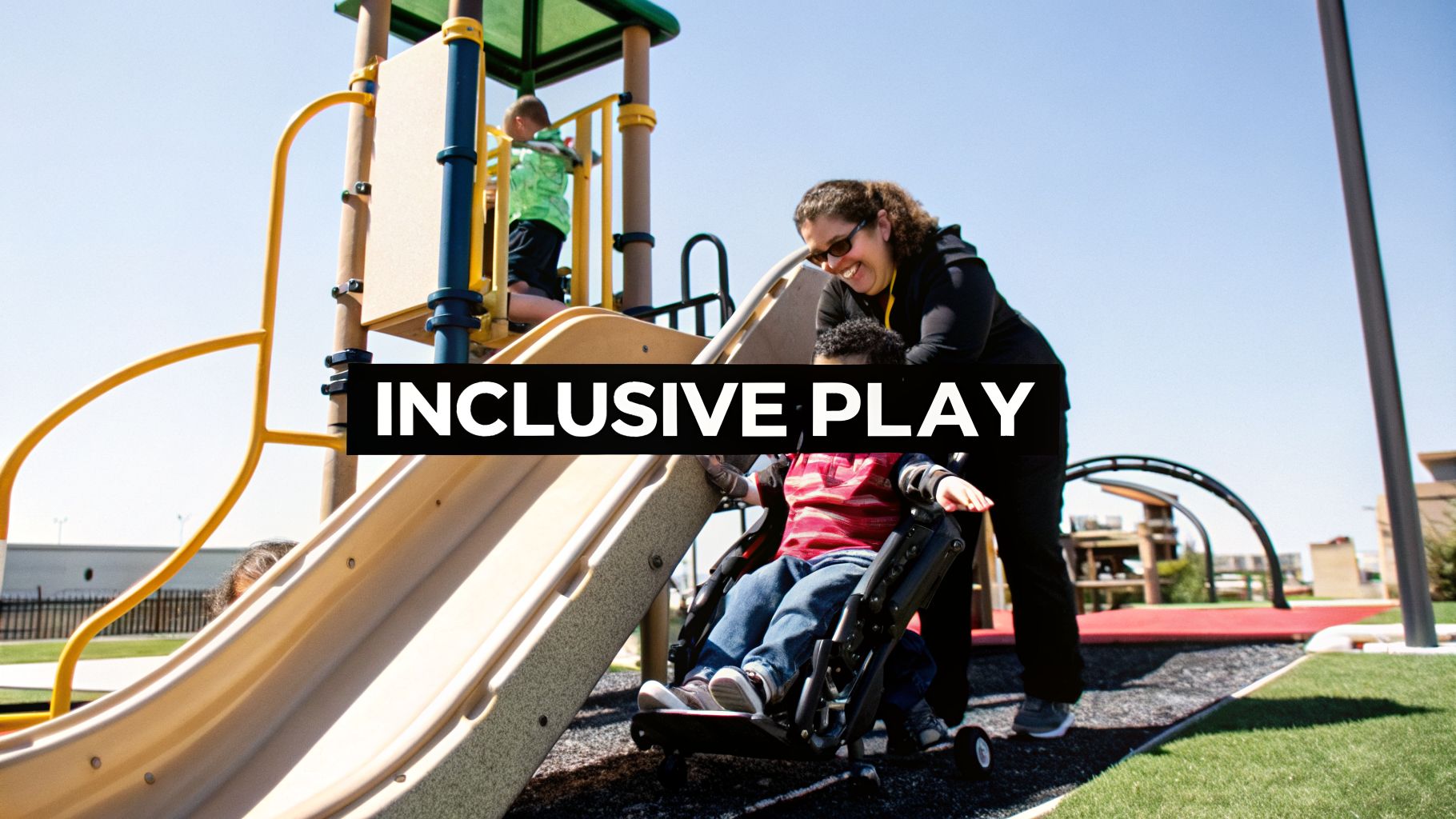 An adult helps a child in a mobility device on an inclusive playground with other children.