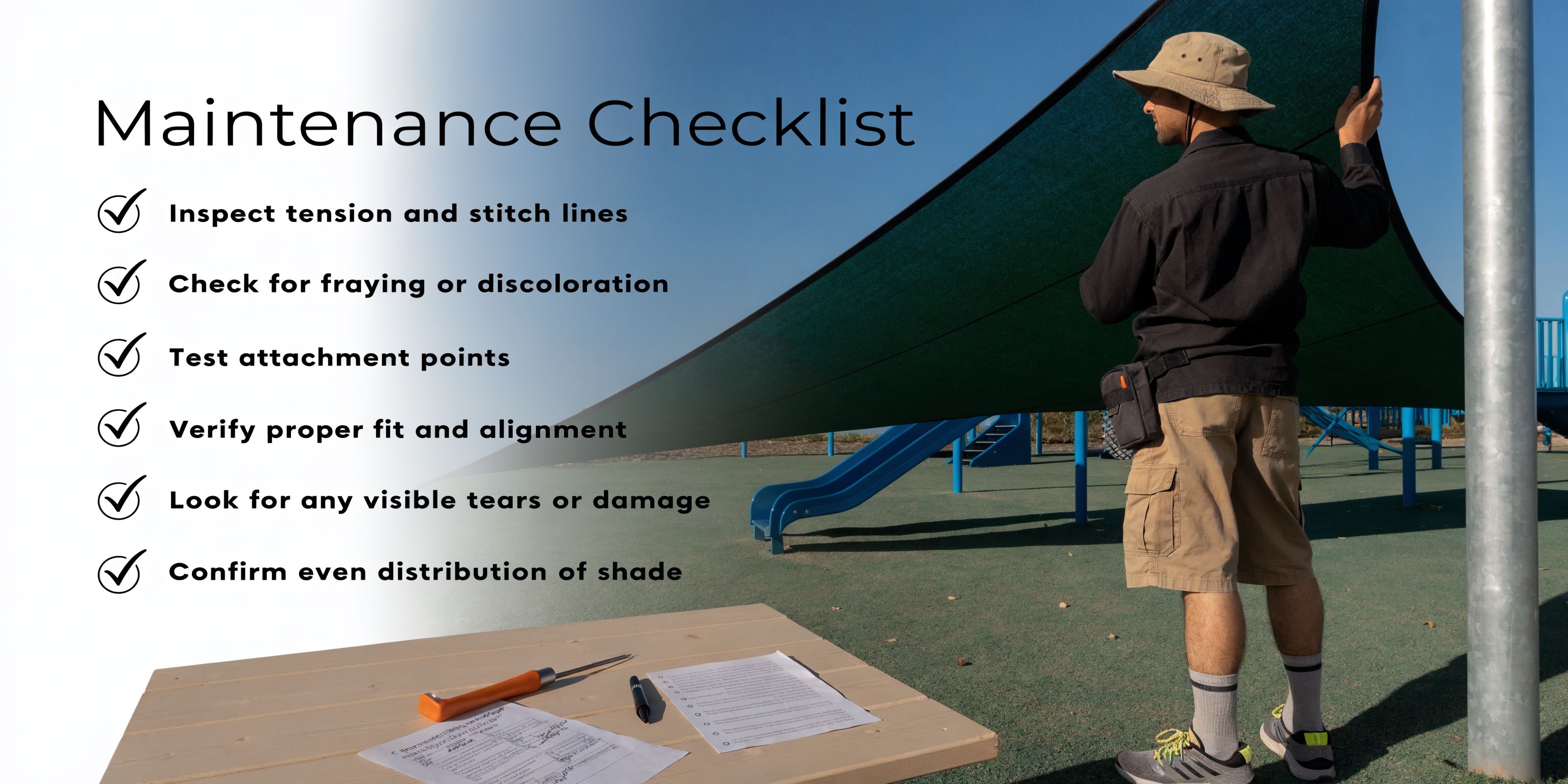 A maintenance technician inspects a playground shade sail structure while referring to a printed checklist on a table.