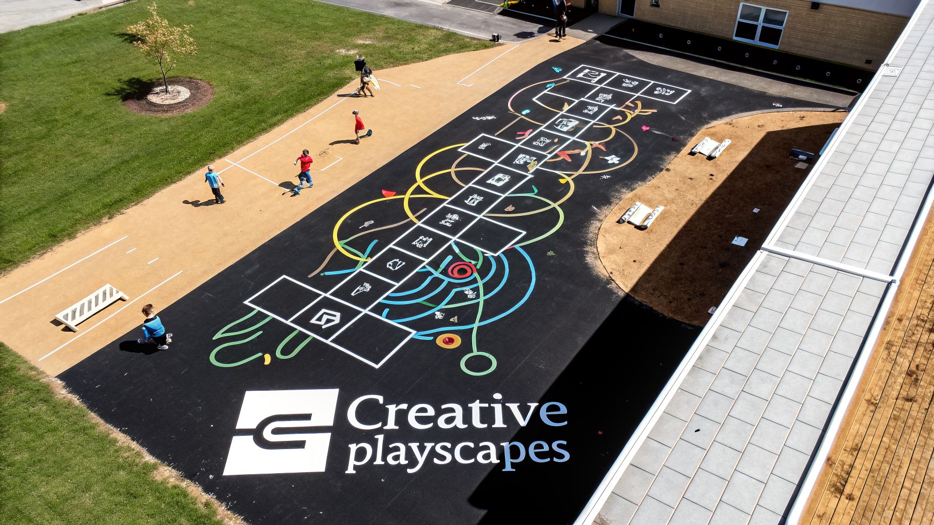 Aerial view of children playing on a vibrant outdoor playground with hopscotch and a Creative Playscapes logo.
